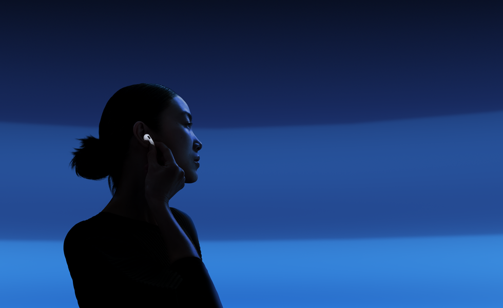 Una persona sujeta la parte alargada de un auricular con el índice y el pulgar para cambiar de modo de escucha en los AirPods 5