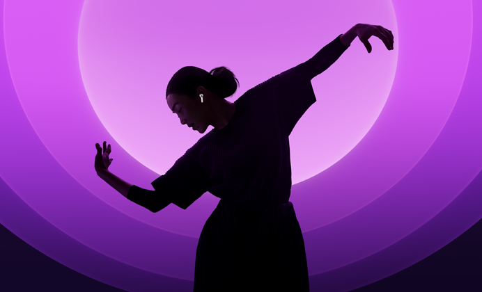 Una persona baila con unos AirPods 5 puestos, fondo multicolor