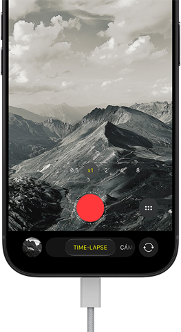iPhone 18 Pro, parte delantera, muestra un paisaje montañoso, ventana superpuesta del modo Cámara en time-lapse, cable de corriente conectado al puerto de carga