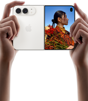 iPhone Duo, color blanco estelar, sujetado por dos manos en horizontal, abierto. Izquierda: sistema de cámaras traseras dual Fusion de 48 Mpx. Derecha: una persona siendo fotografiada en la pantalla exterior. La persona fotografiada puede verse en la pantalla con Duo Preview mientras le hacen la foto.