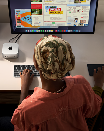 Una persona utiliza un Mac mini con Magic Keyboard, Magic Trackpad y Studio Display conectado en un escritorio