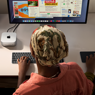 Una persona utiliza un Mac mini con Magic Keyboard, Magic Trackpad y Studio Display conectado en un escritorio