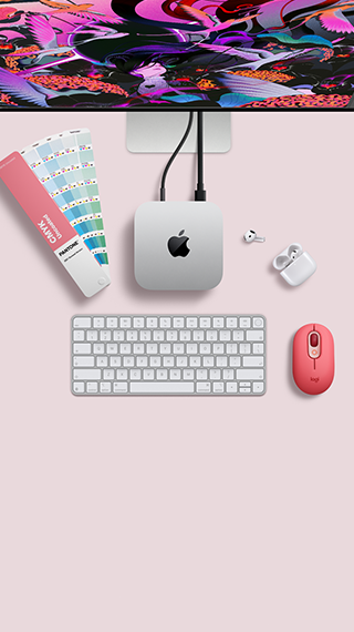 Mac mini, vista superior, muestra el aluminio en plata, las esquinas redondeadas, el logotipo negro y brillante de Apple en el centro, el cable de conexión, la parte superior del Studio Display, los AirPods 4 abiertos, las tarjetas de colores Pantone y el teclado y el ratón Logitech rojos