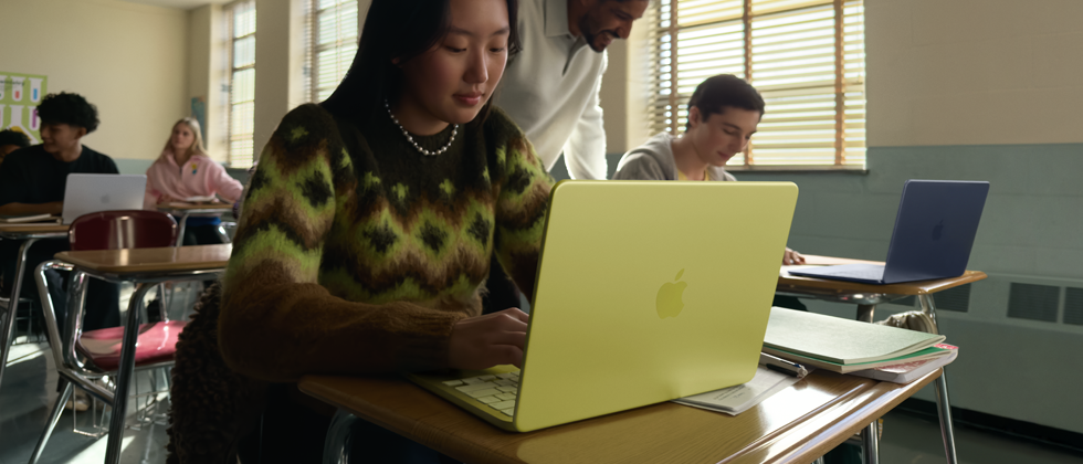 Estudiante utilizando un MacBook Neo, color cítrico, portátil sin enchufar en un aula
