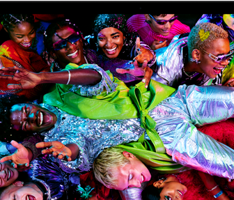 MacBook Pro con la pantalla a todo color que muestra a una persona llevada en volandas en una fiesta, destaca la nitidez de la pantalla Liquid Retina XDR