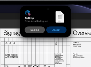 La pantalla muestra la Dynamic Island con una petición de AirDrop en una ventana pequeña sobre un archivo abierto de Adobe Acrobat